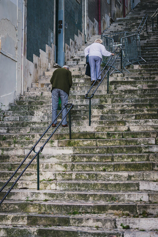 dvoje ljudi uspinje se strmim lisabonskim stepenicama