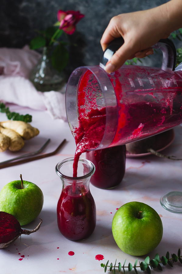 pouring the beetroot apple ginger smoothie in the glass