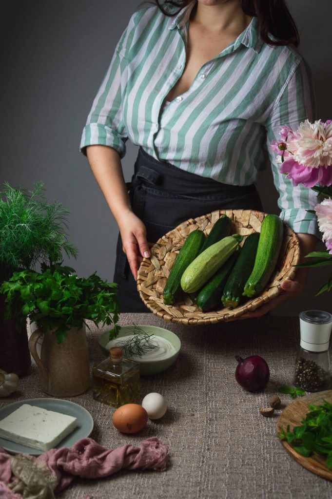 woman holding fresh zucchini in the basket