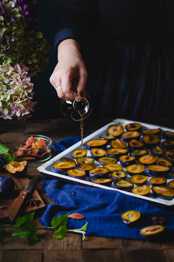 pouring dessert wine over blue damson plums before roasting