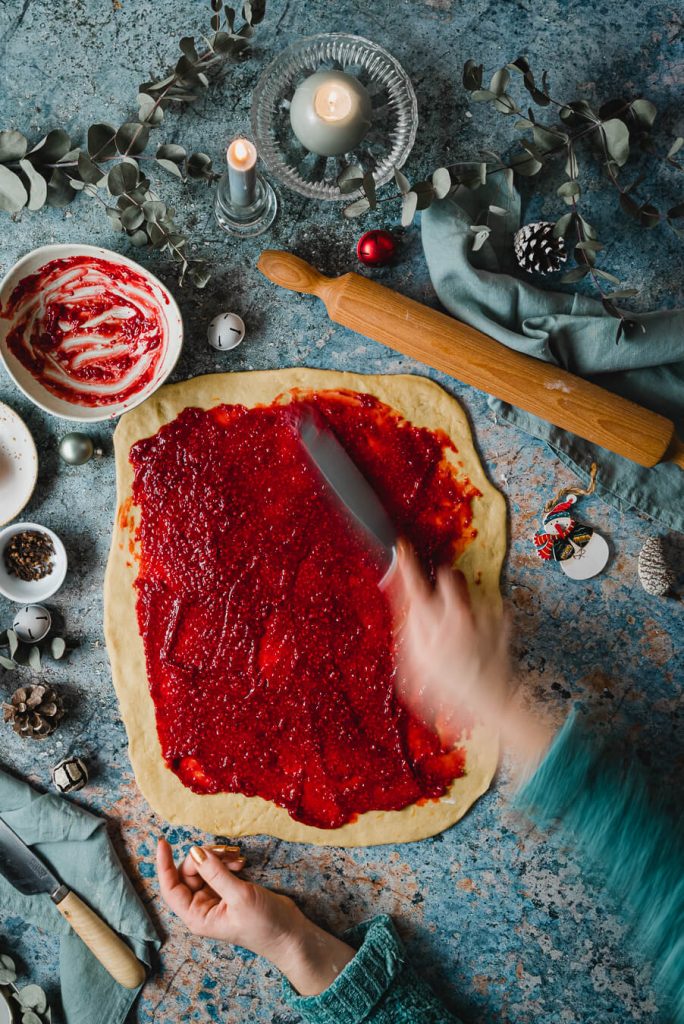 spreading raspberry jam over brioche dough
