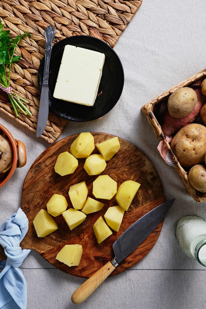 cut and peeled potatoes on cutting board ready to be cooked