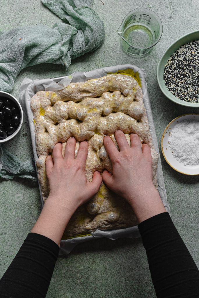 making dimples with fingers in whole wheat focaccia dough