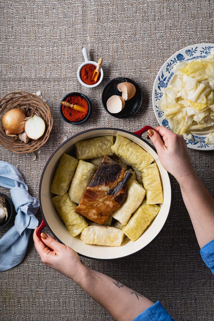 sarma cabbage rolls layered tightly in the pot with a piece of dried cured meat