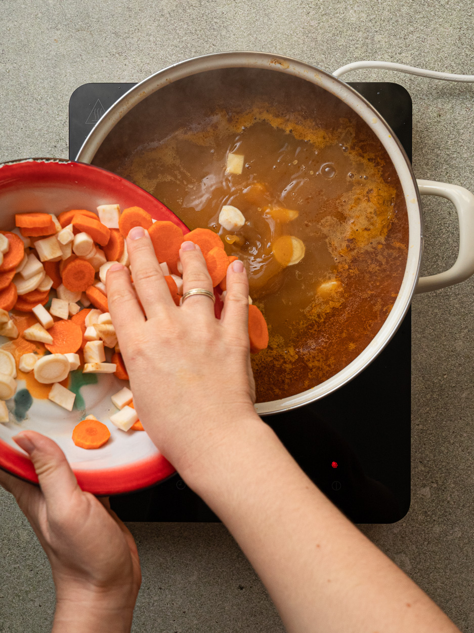 adding root vegetables to the stew