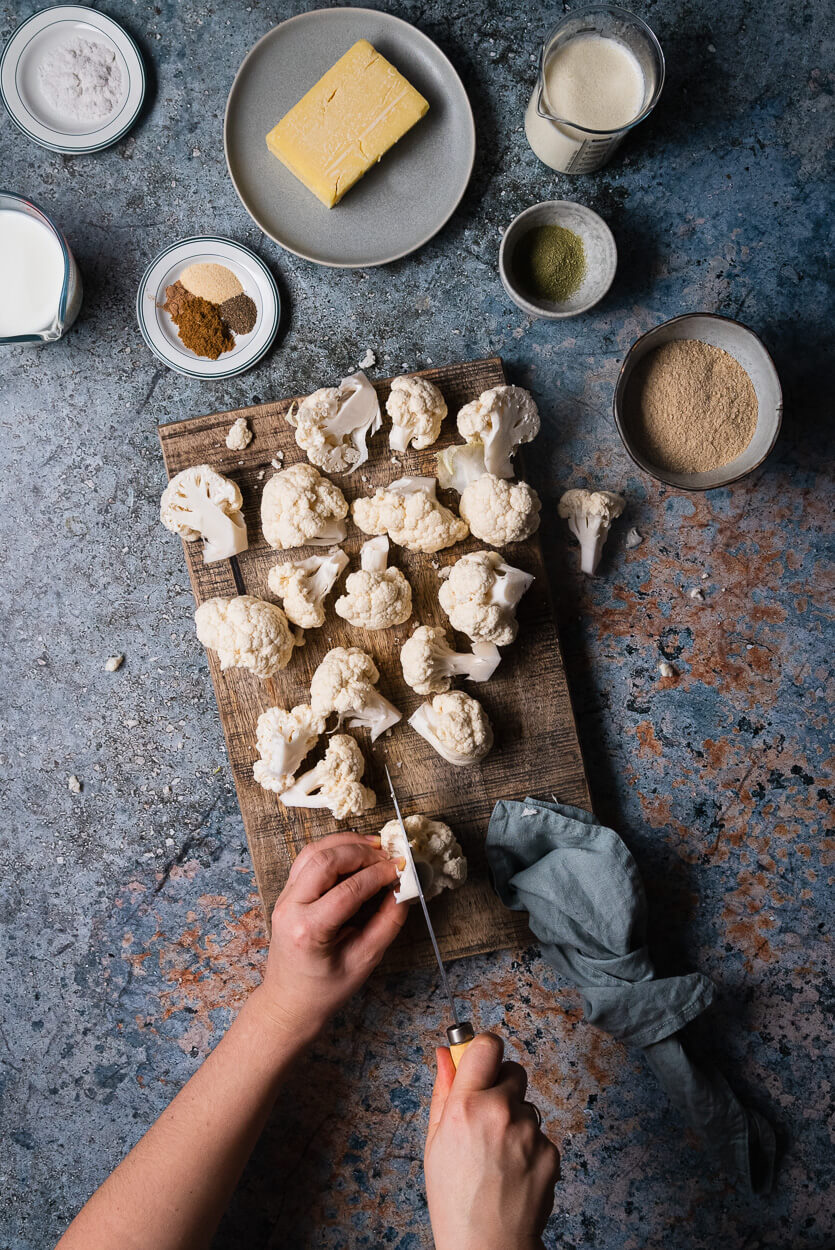 ingredients for making the cheesy roasted cauliflower with cauliflower florets on a wooden board