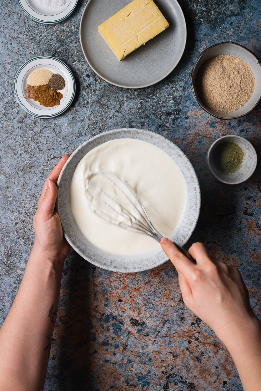 stirring heavy cream, milk and sour cream in a bowl with a whisk