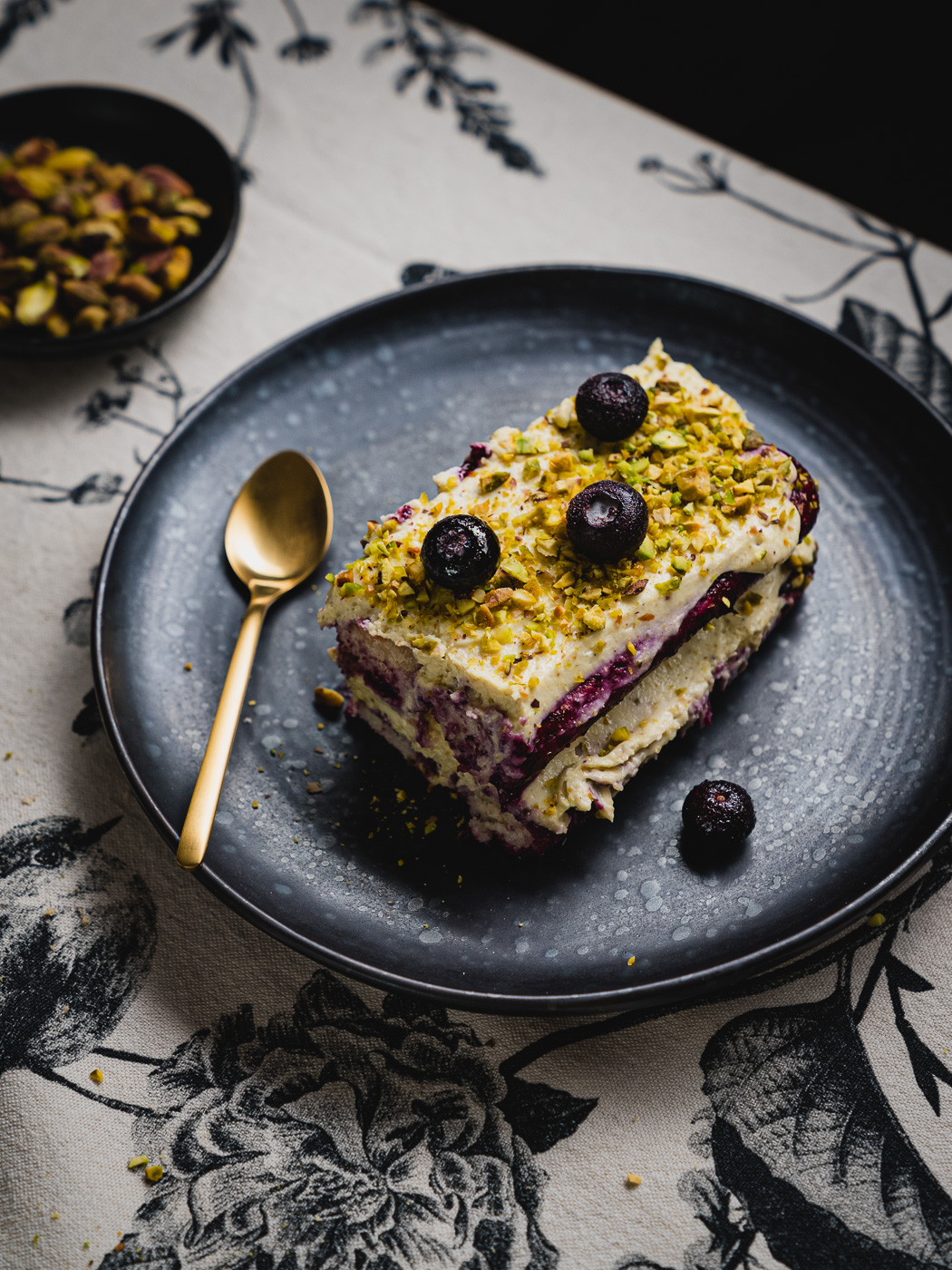 pistachio blueberry tiramisu served on black dessert plate