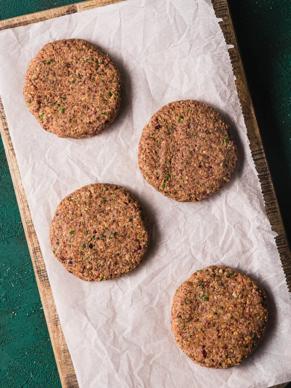 oblikovani veganski burgeri (polpete) od graha i gljiva, posloženi na papir za pečenje