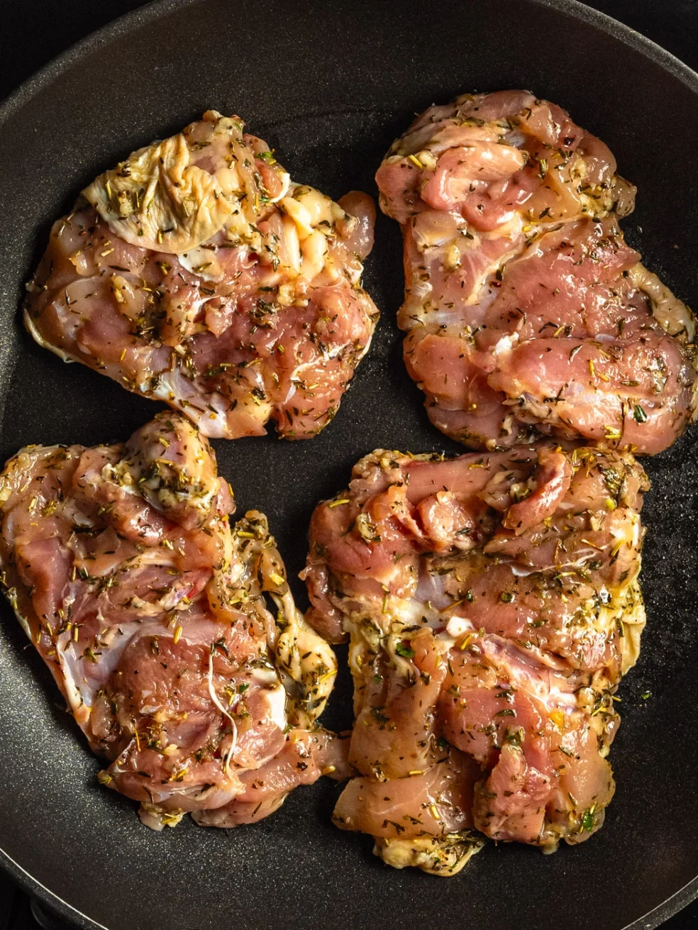 chicken thighs cooking in a pan, skin side down