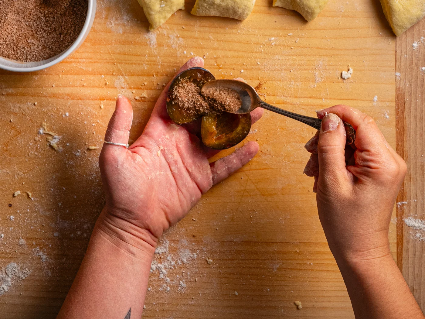 adding spiced sugar into halved plums