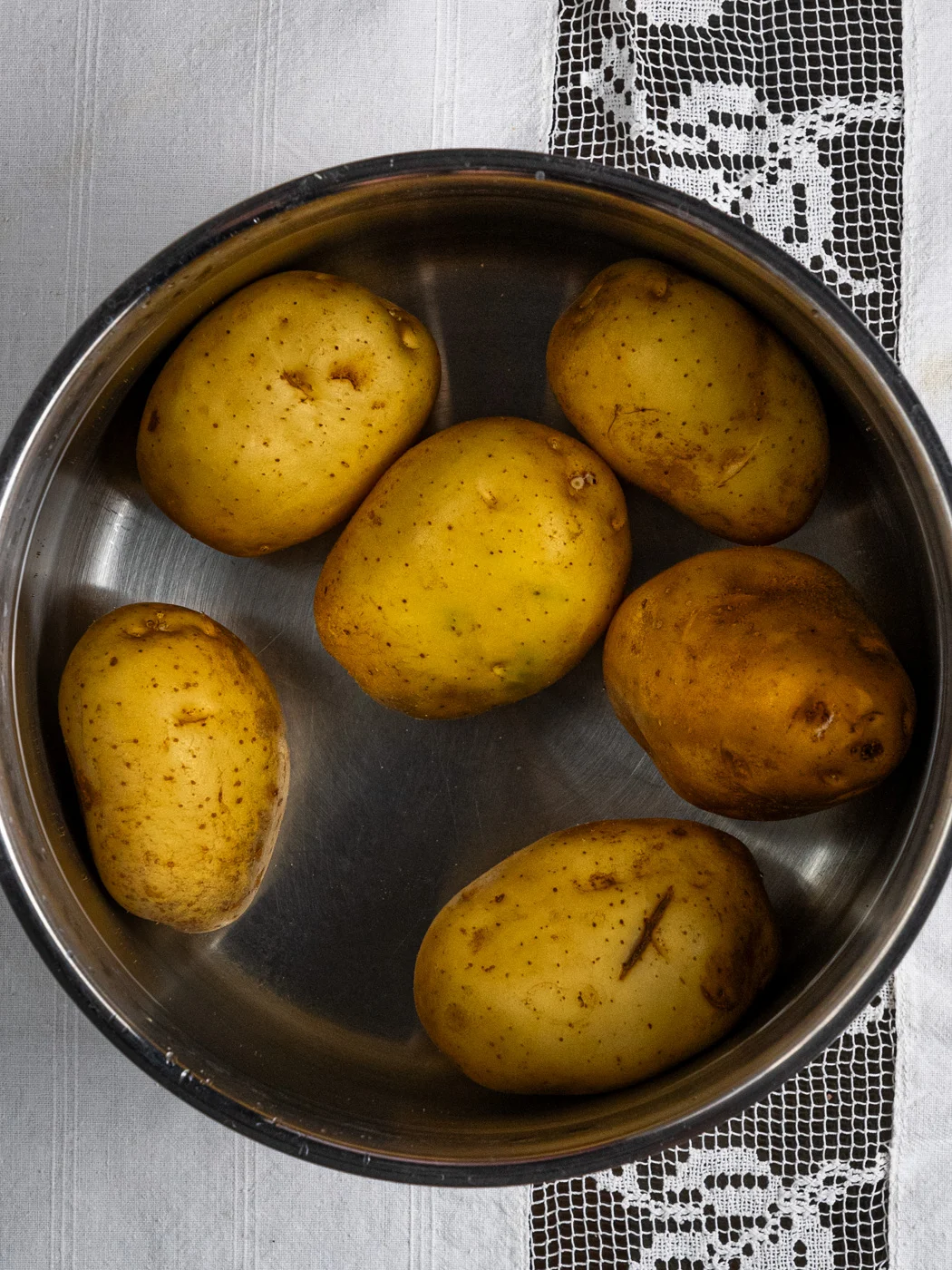yellow potatoes in a cooking pot, submerged in water