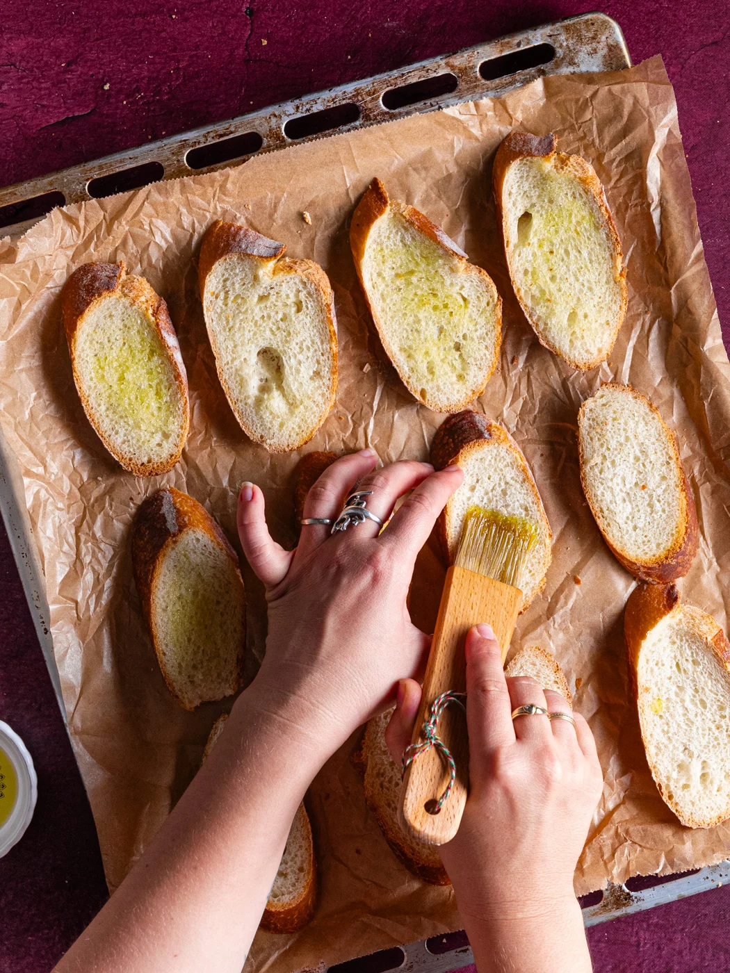 arranged baguette slices on baking tray, brushing with olive oil