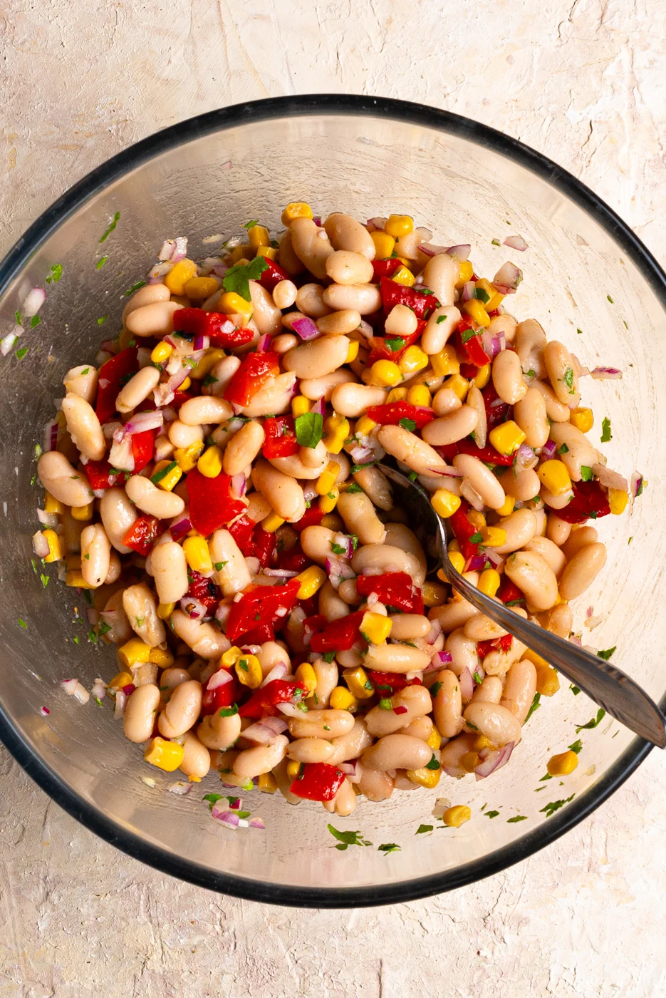 marinated white beans with corn and red pepper fillets in a big glass bowl